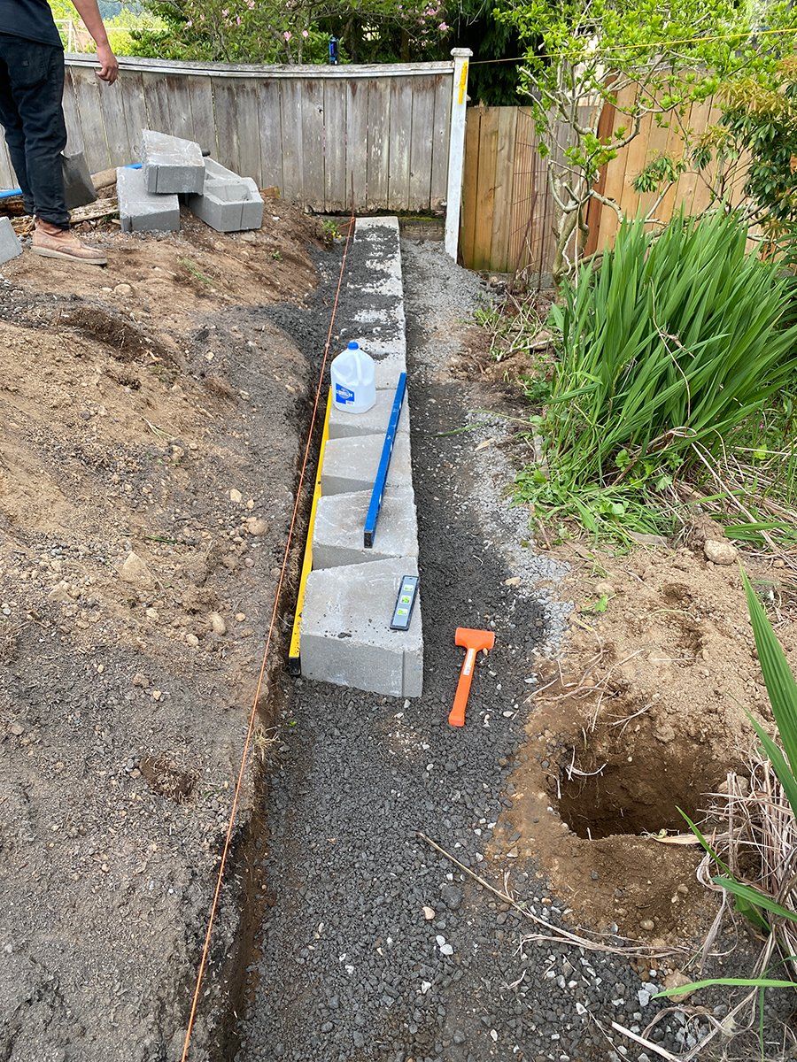 A person is digging a hole in the ground next to a fence.