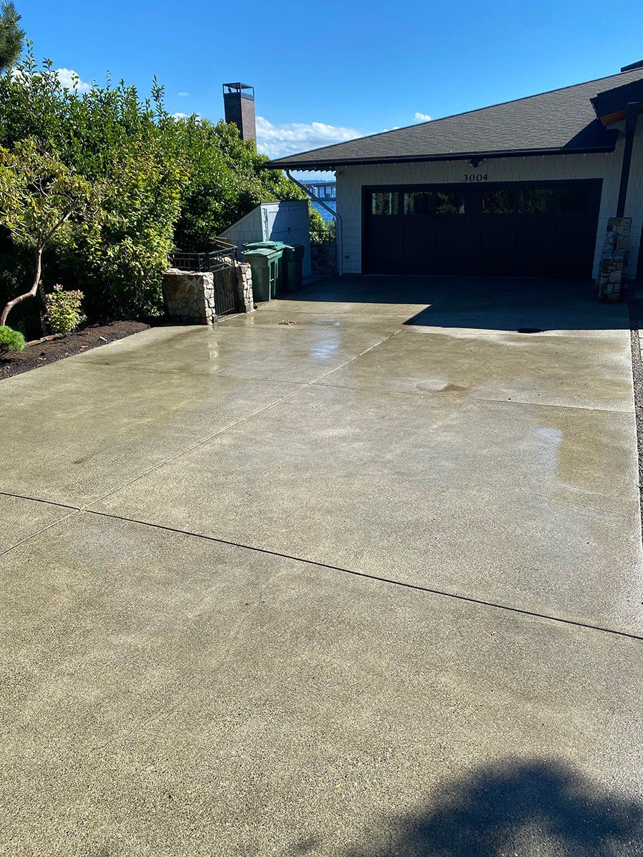 A concrete driveway in front of a house with a garage door.