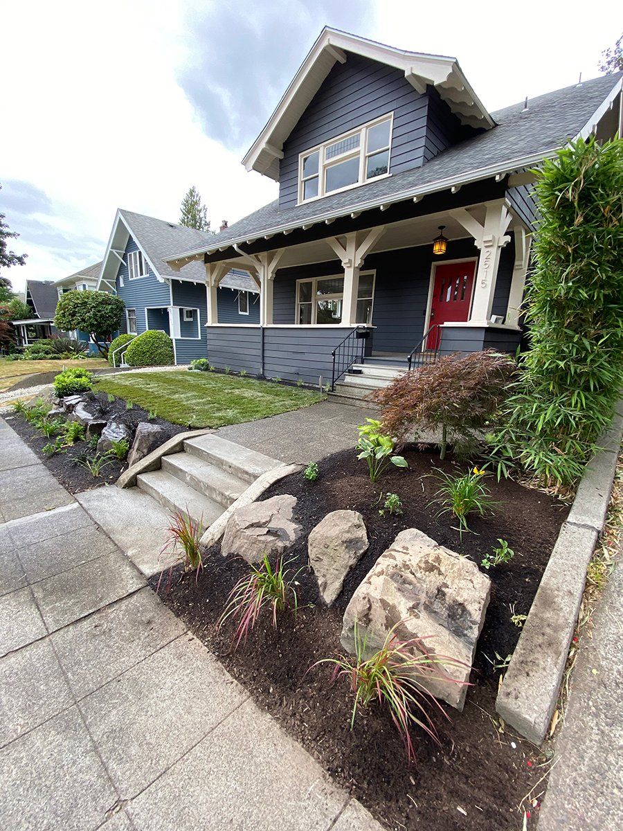 A blue house with a red door and a stone walkway in front of it.