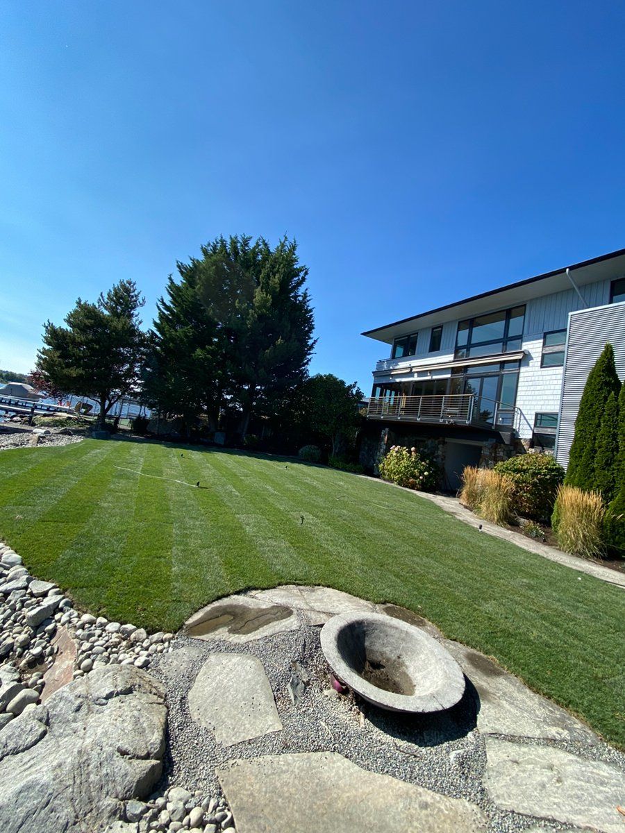 There is a fire pit in the middle of a lush green lawn in front of a house.