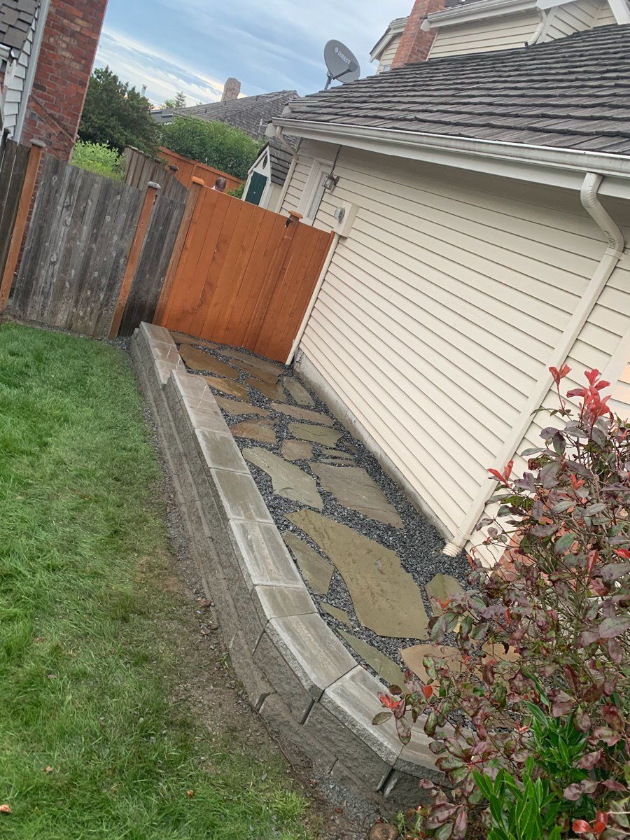 A stone walkway leading to a house with a wooden fence.