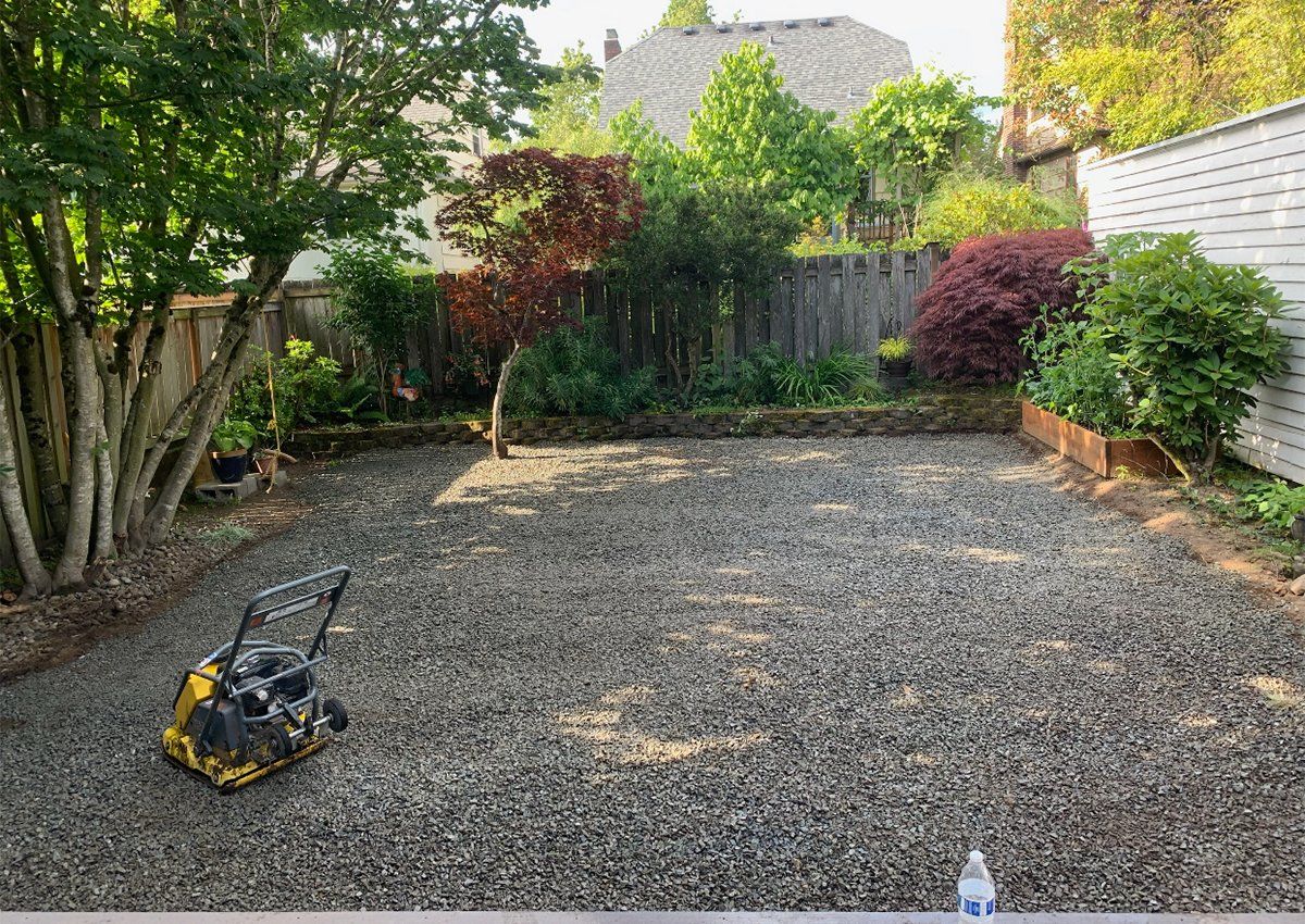 A gravel driveway with a yellow machine in the middle of it.