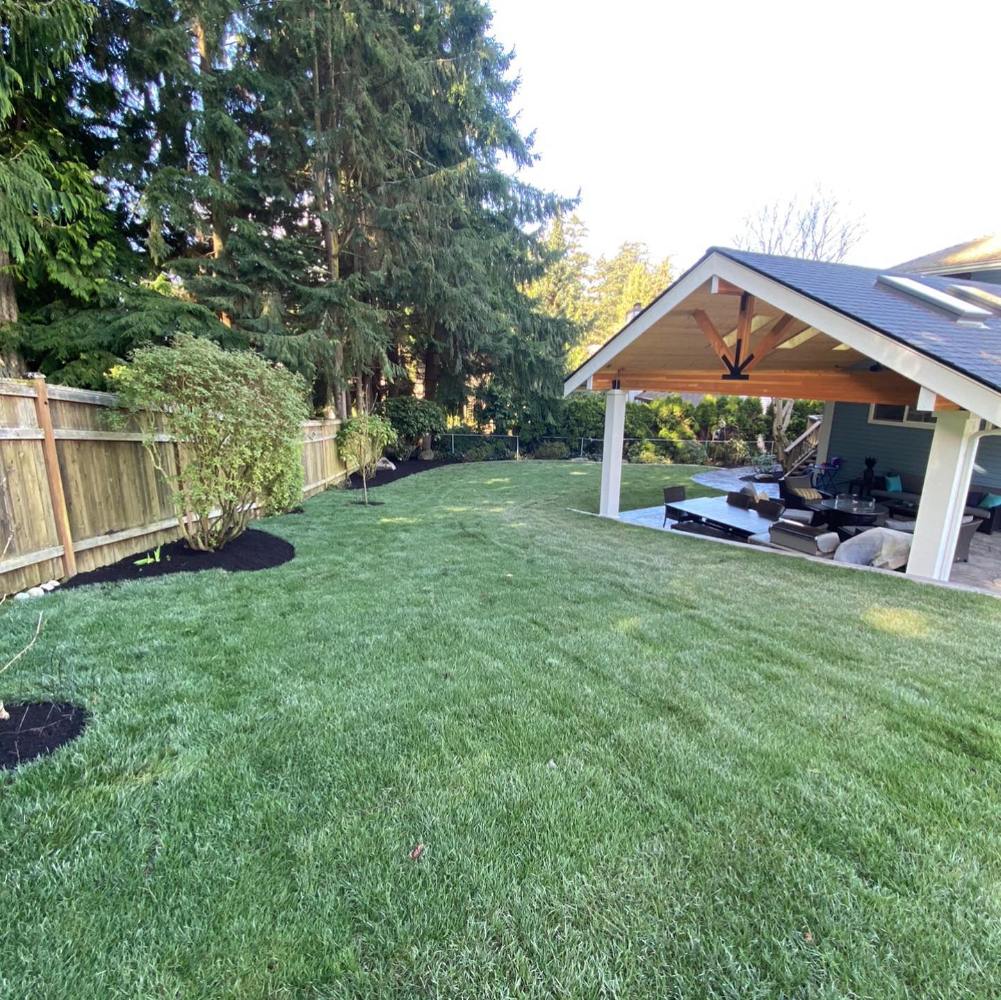 A backyard with a pavilion and a lush green lawn.