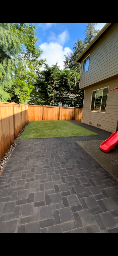 A backyard with a brick patio and a slide.