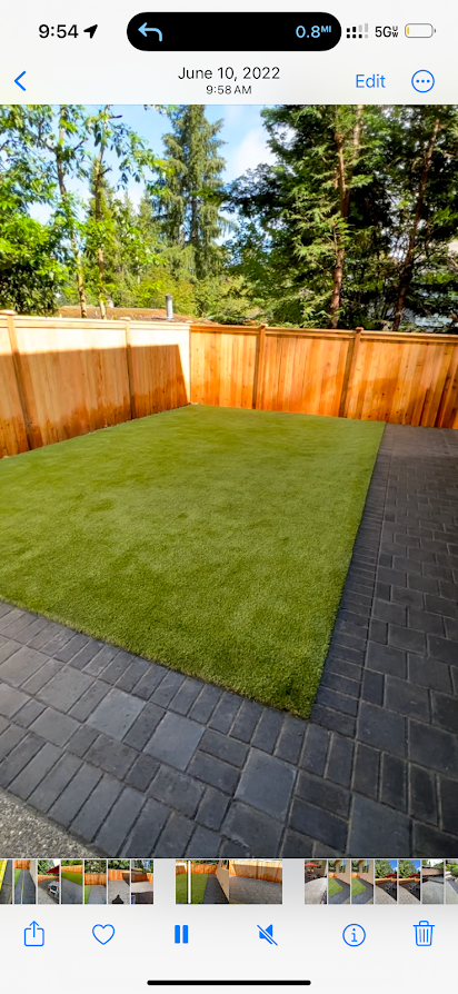 A phone screen shows a picture of a lawn with a wooden fence.