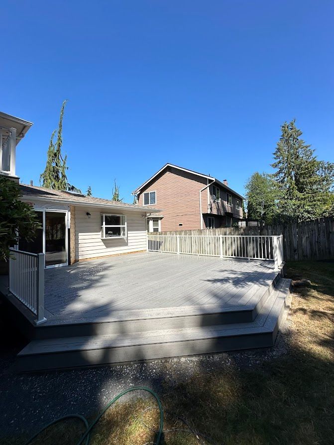 There is a large deck in the backyard of a house.