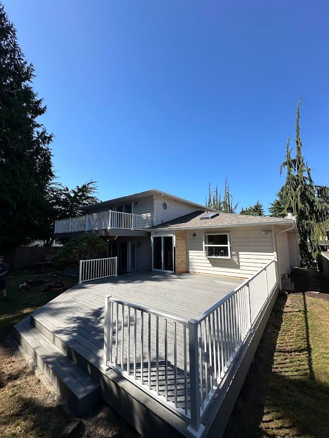 The back of a house with a large deck and a white railing.