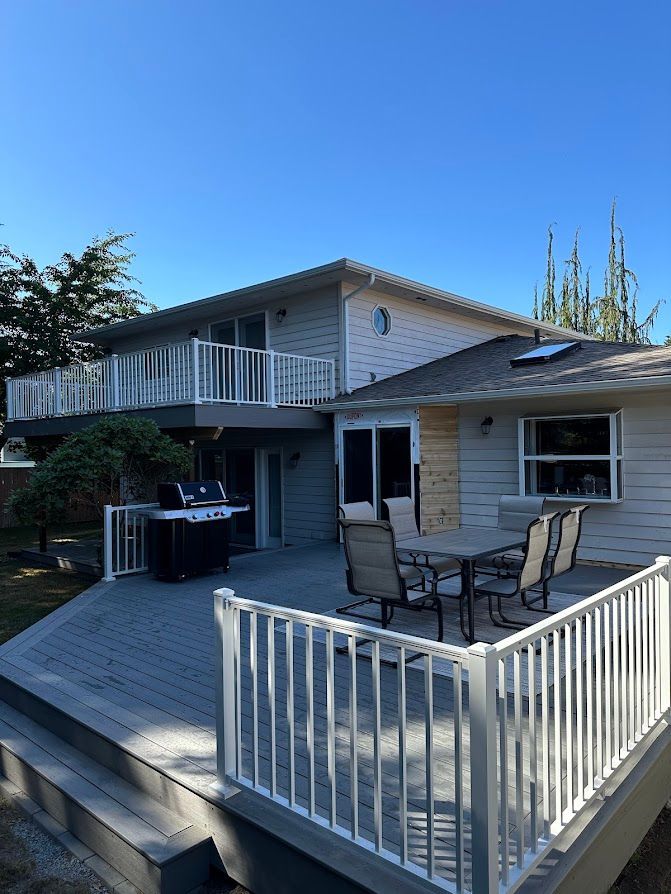 A house with a large deck with a table and chairs on it