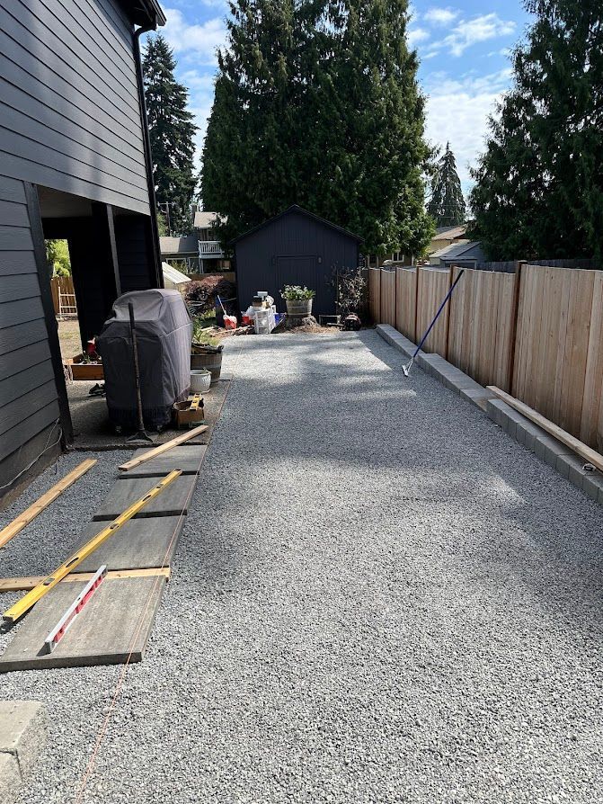 A gravel driveway is being built in front of a house.