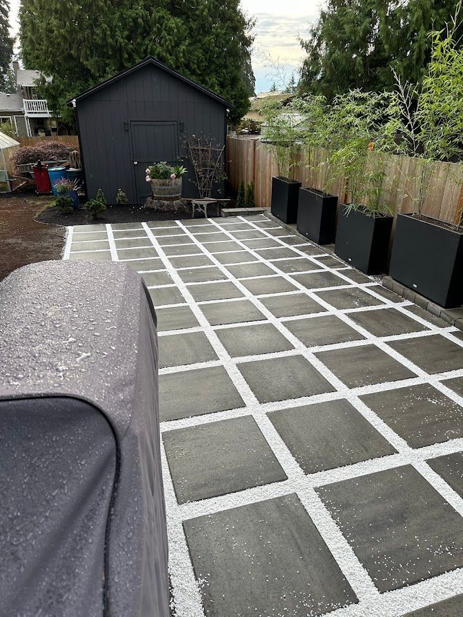 A patio with white lines on it and a black shed in the background.