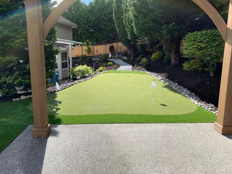 A putting green in a backyard with a house in the background