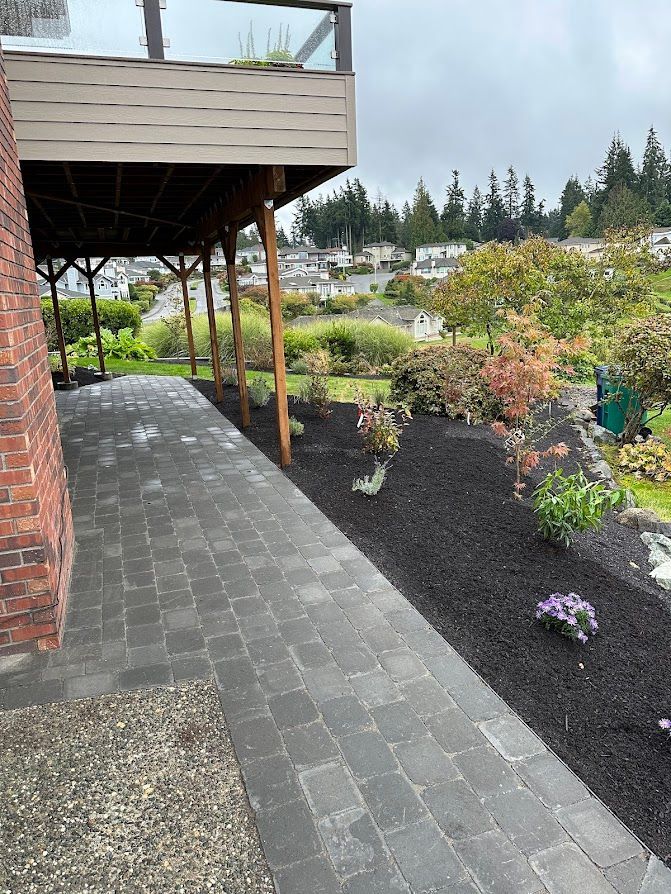 A brick walkway leading to a house with a deck.