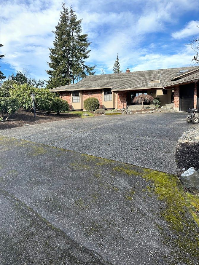 A large brick house with a large driveway in front of it.