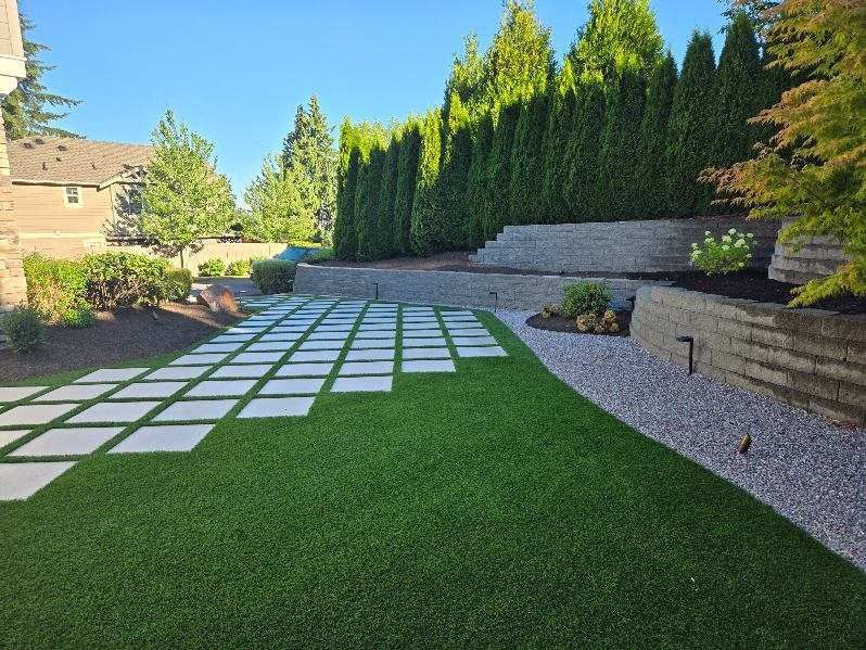 A backyard with a lush green lawn and a stone walkway.