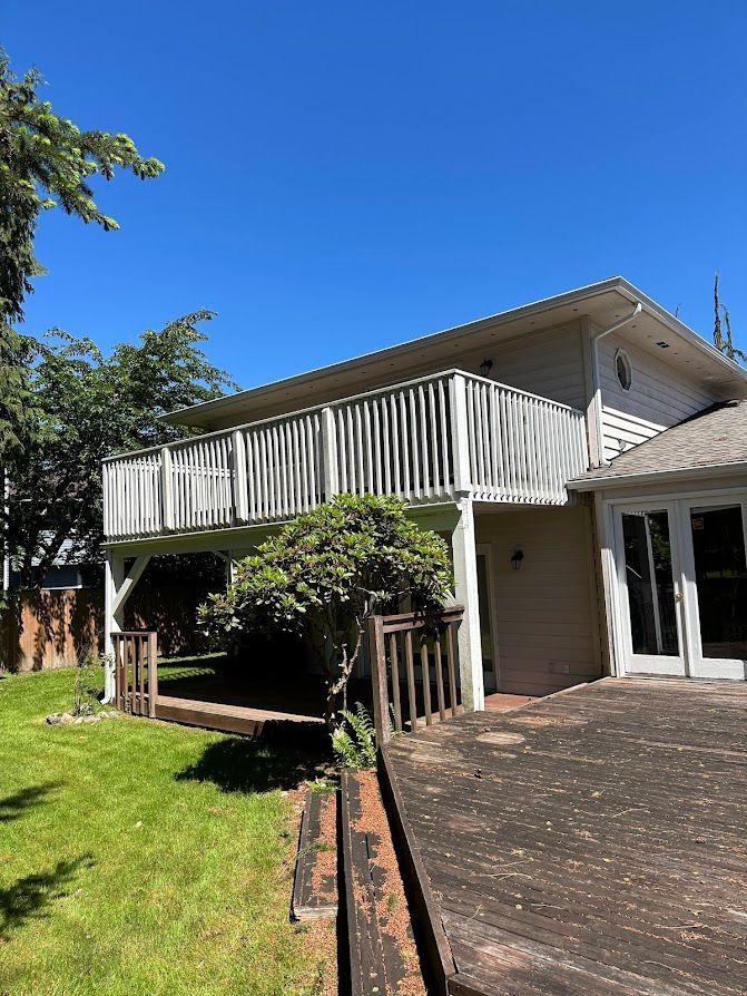 The back of a house with a large deck and a large balcony.
