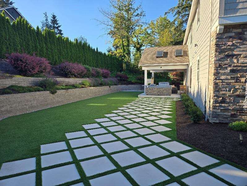 A stone walkway leading to a house with a lush green lawn