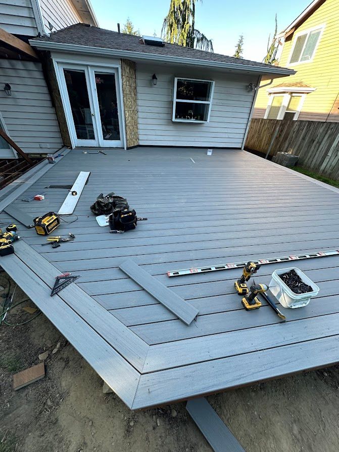 A gray deck is being built in front of a house.
