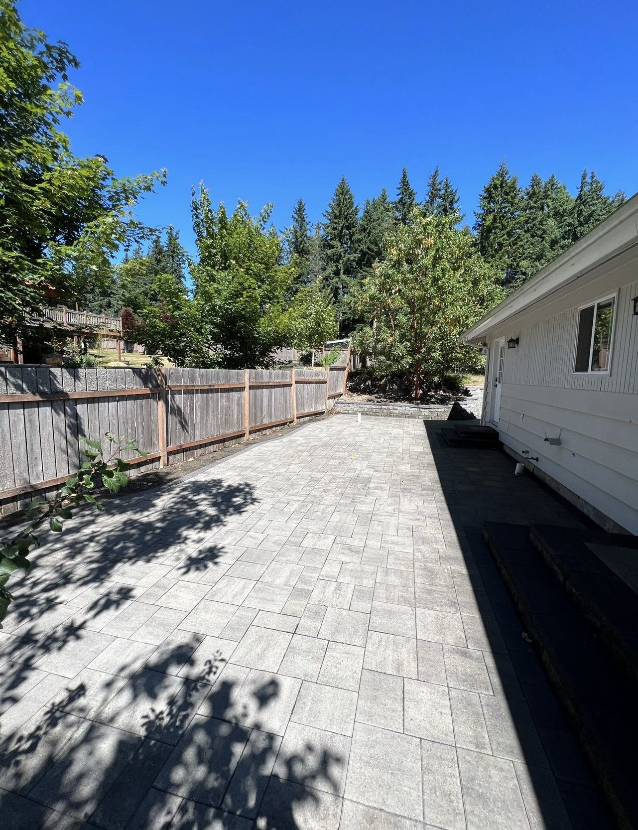 A driveway leading to a house with a wooden fence