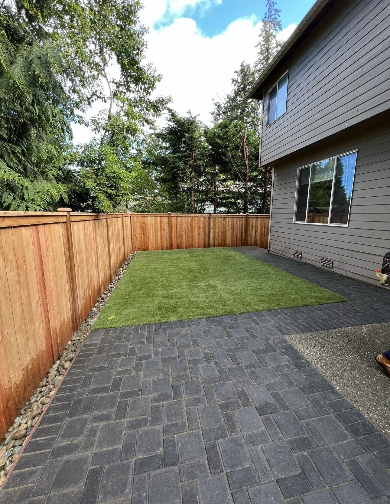 A backyard with a brick walkway and a wooden fence.
