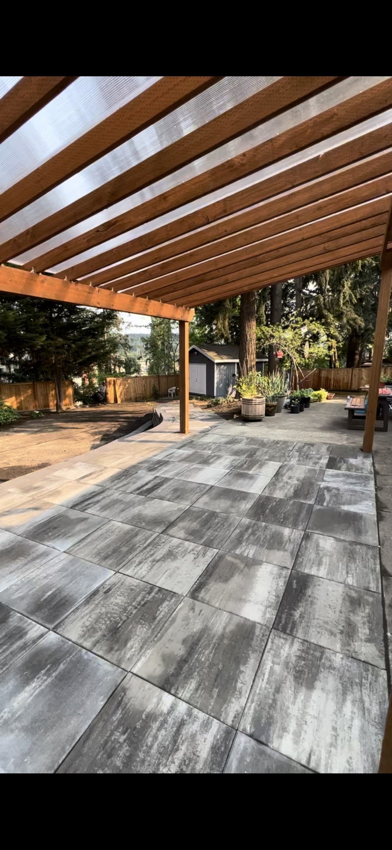 A large patio with a wooden pergola over it.