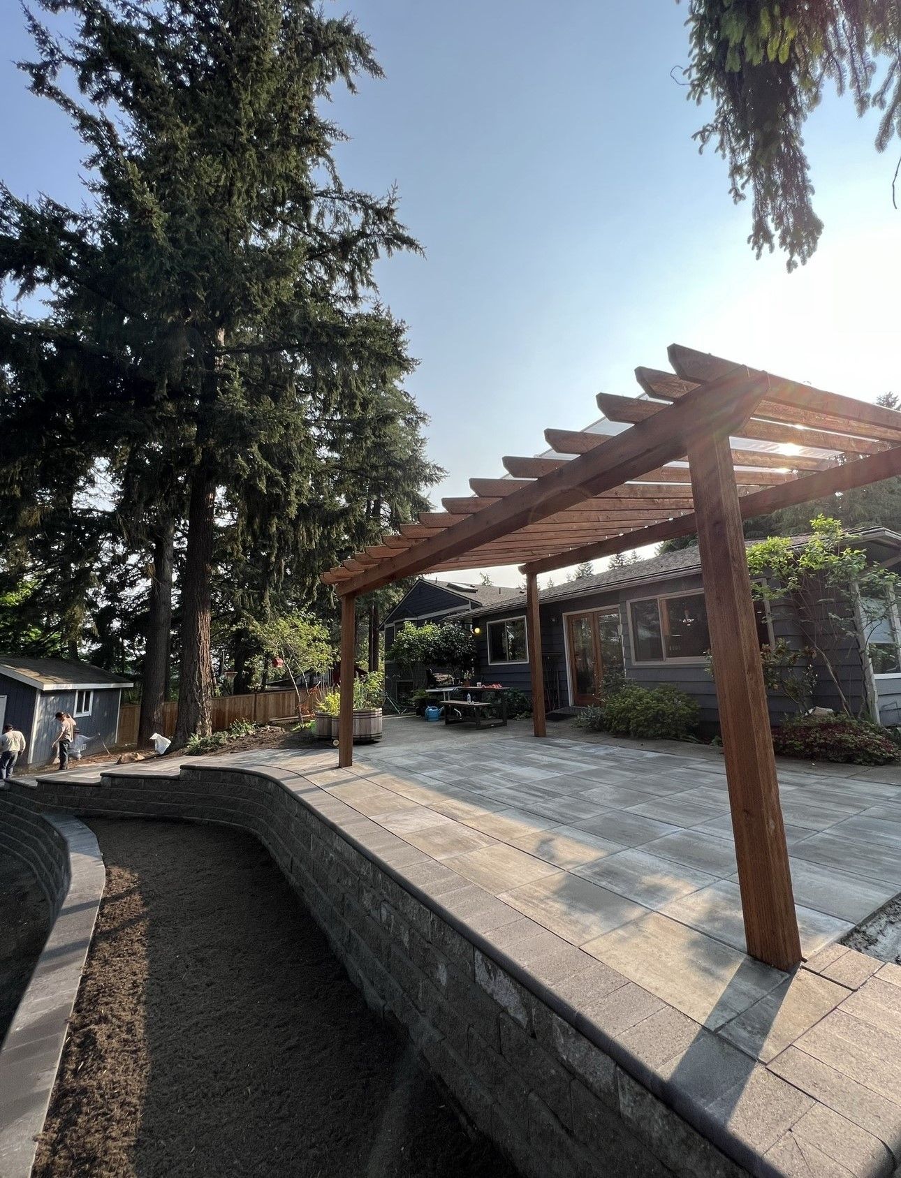 A wooden pergola is in the backyard of a house.