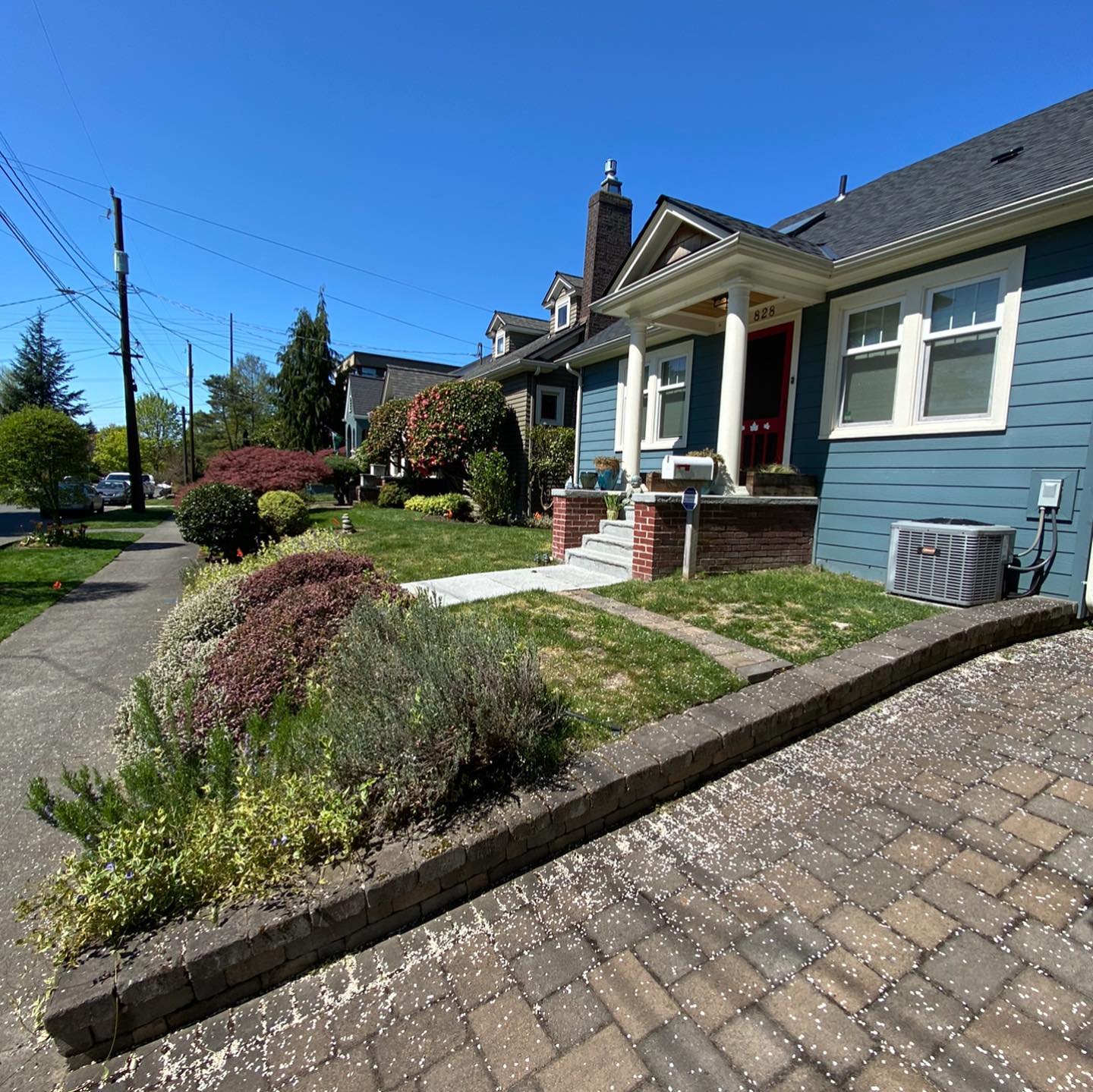 A blue house with a porch and a brick driveway