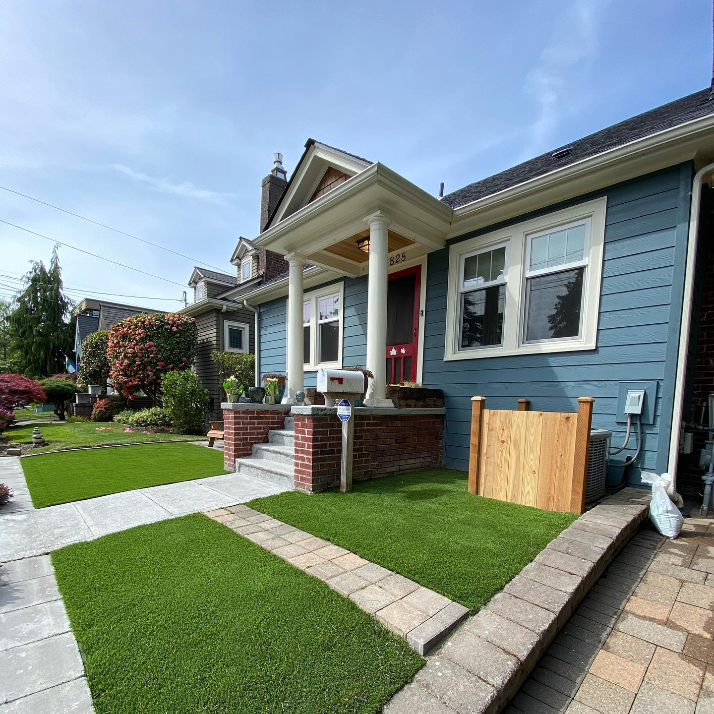 A blue house with a brick porch and a lush green lawn.