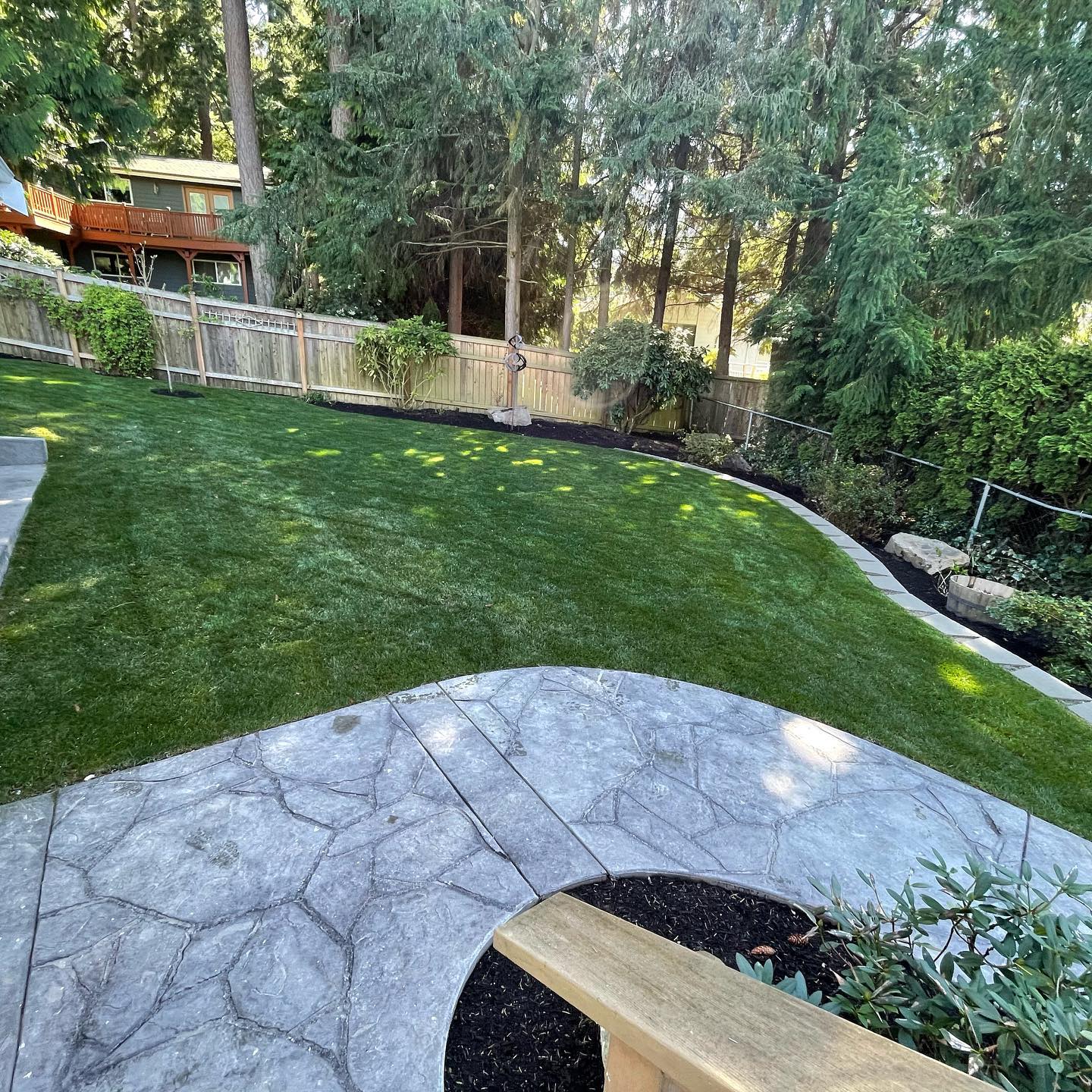 A backyard with a patio and a lush green lawn.