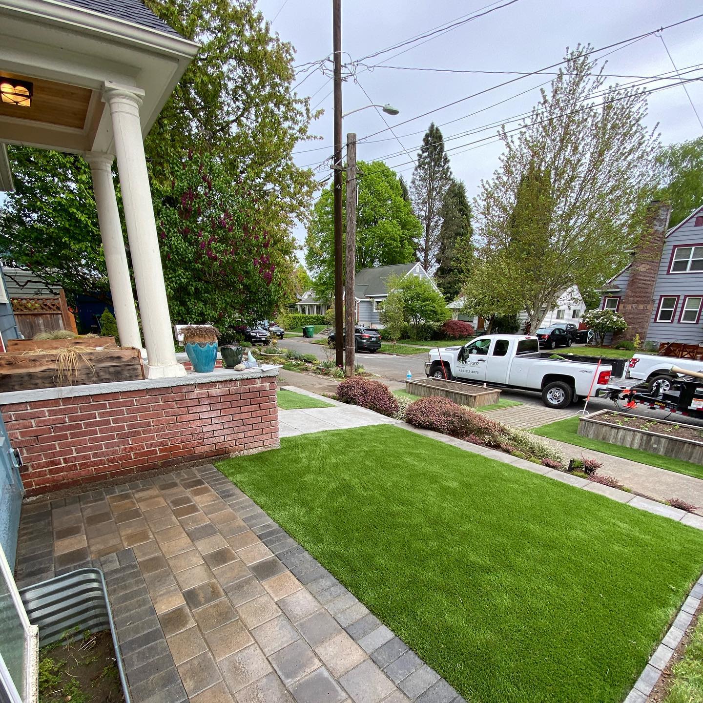 A white truck is parked on the side of the road in front of a house.