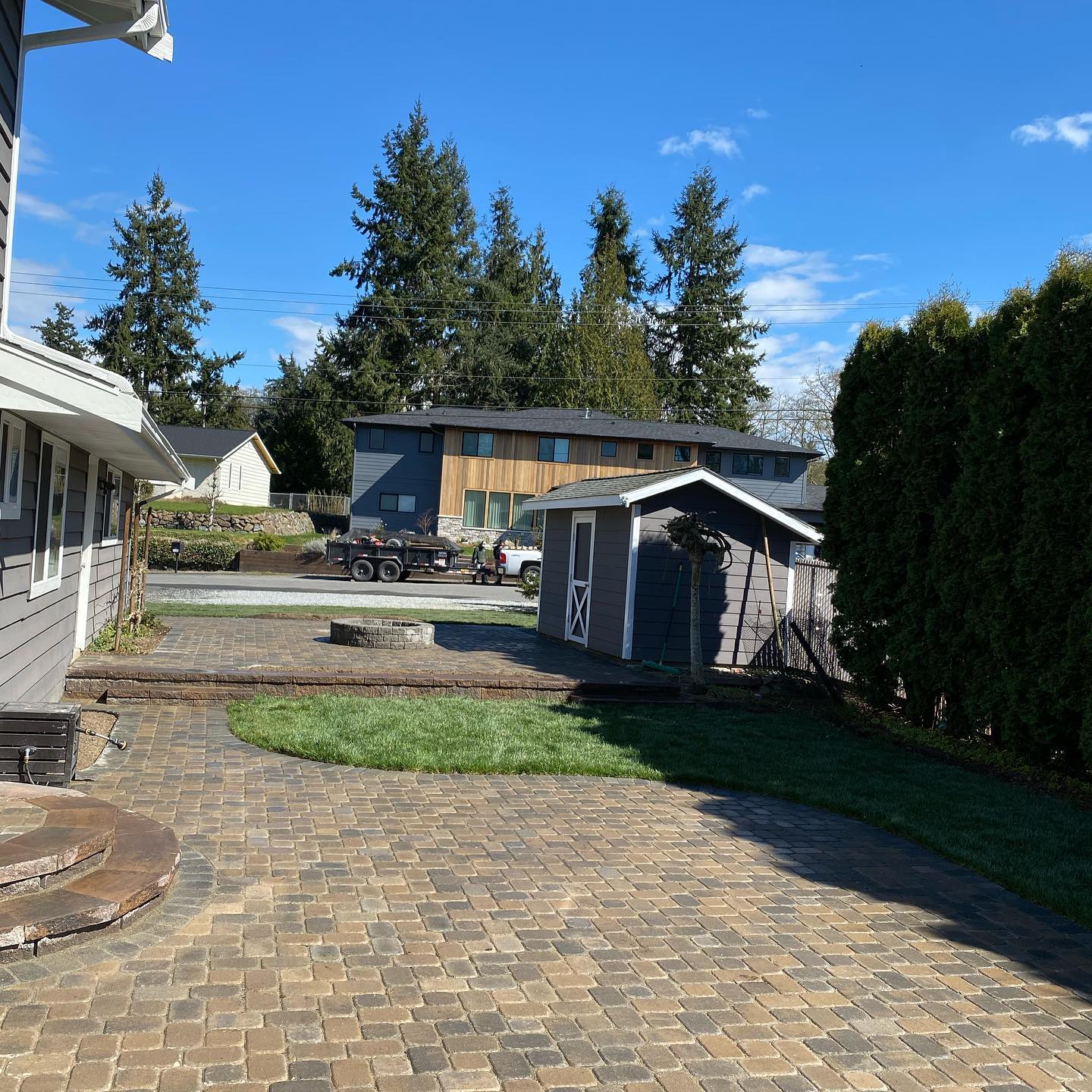 A brick driveway leading to a house with a shed in the backyard