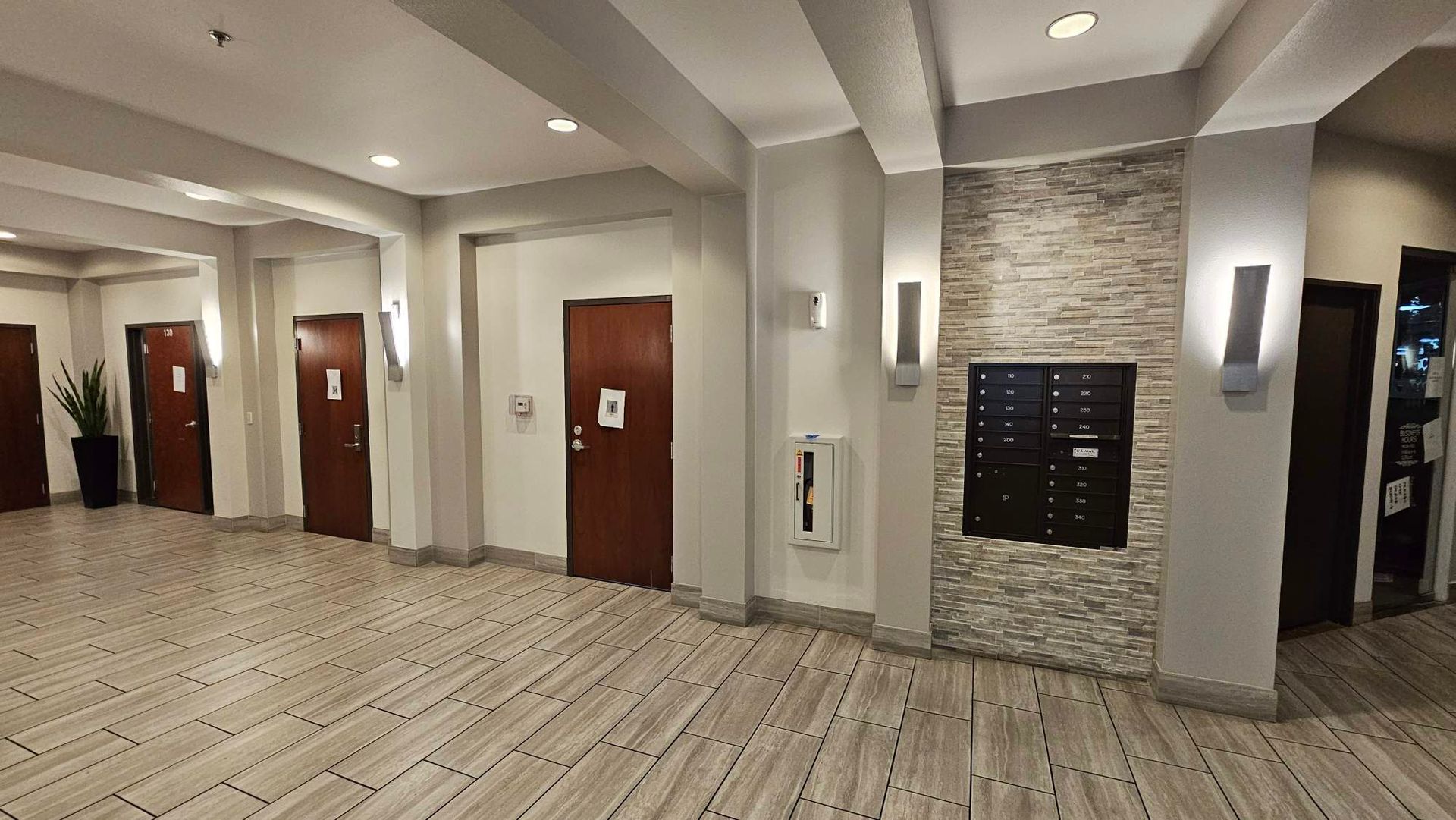 Hallway with apartment doors, mailboxes, and stone accent wall.