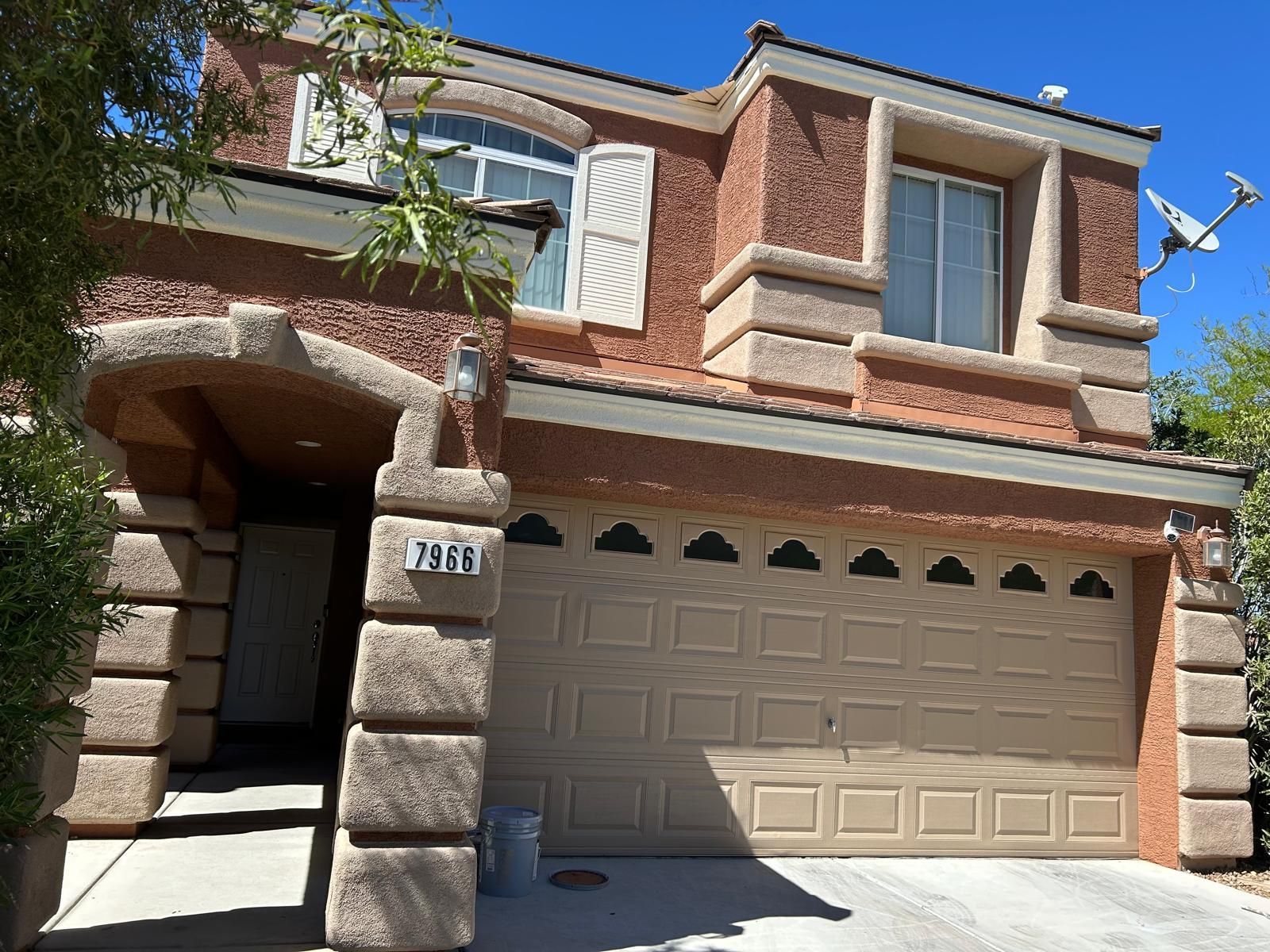 Two-story brick house with beige garage door and columns.