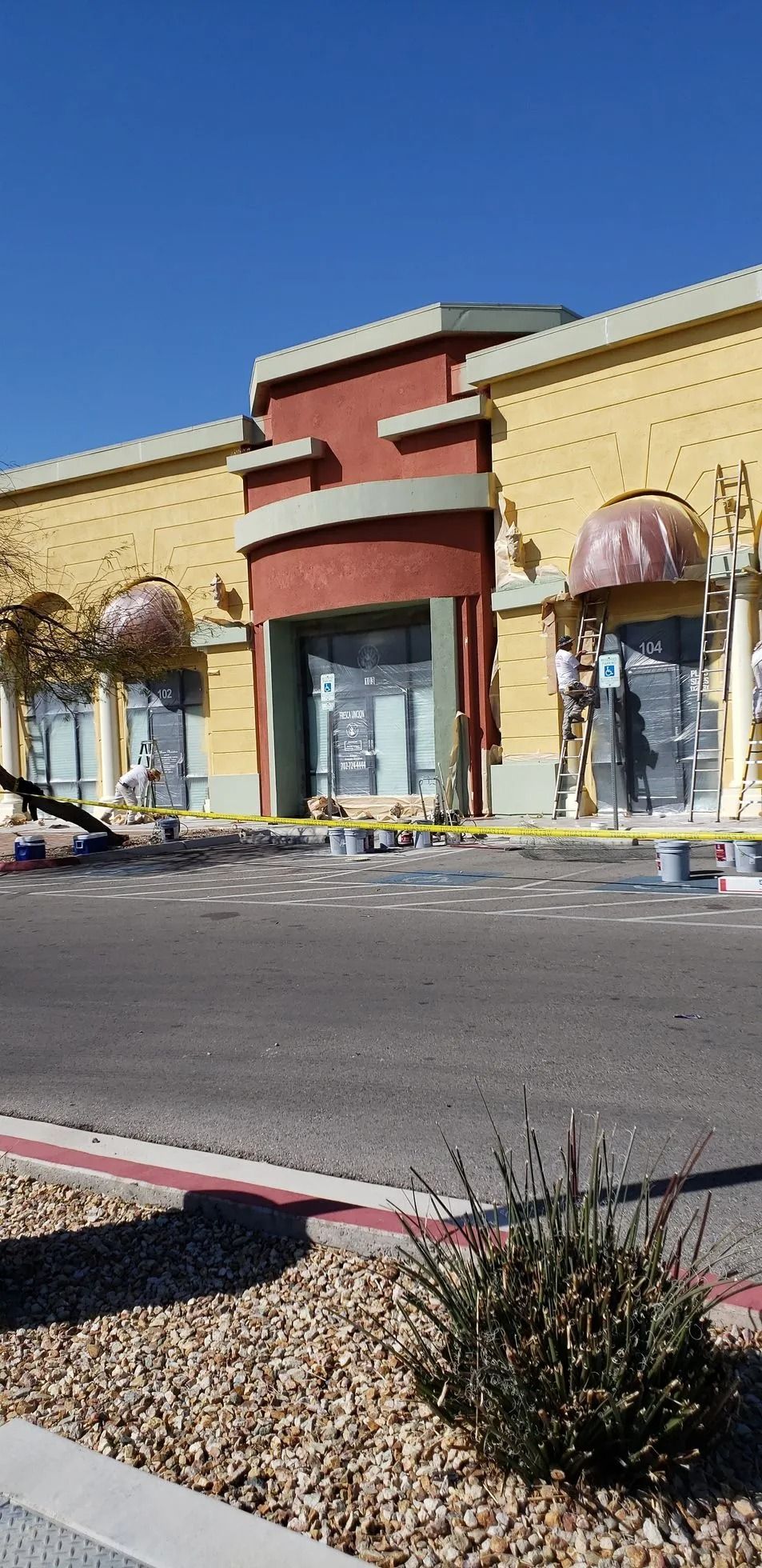 Commercial building exterior with yellow and red facade, clear blue sky.