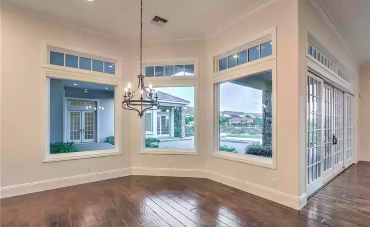 Bright dining room with large windows, dark wood floor, and chandelier.