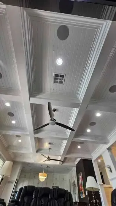 Ornate white ceiling with recessed lighting and two ceiling fans.