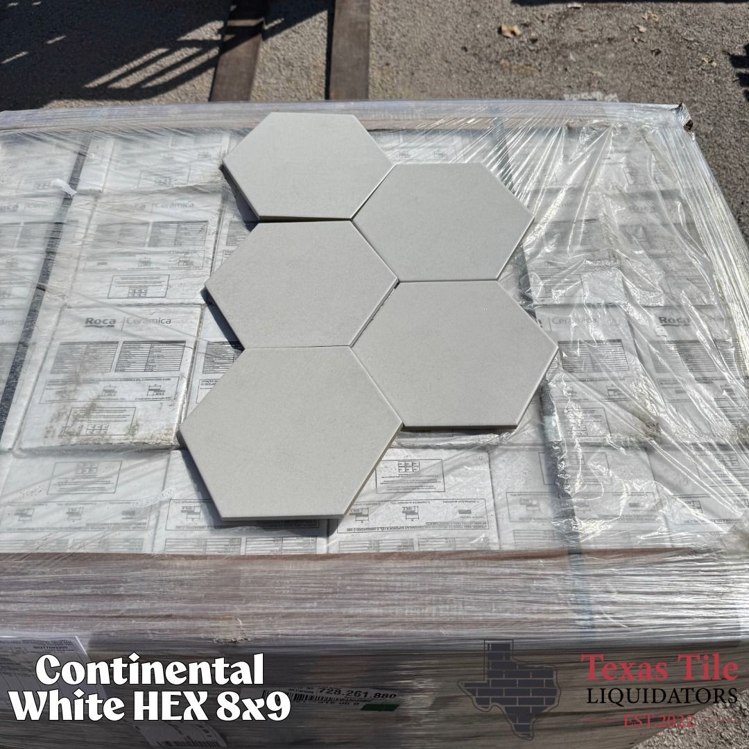 Stack of white hexagonal tile samples on a wrapped pallet with product labels visible.