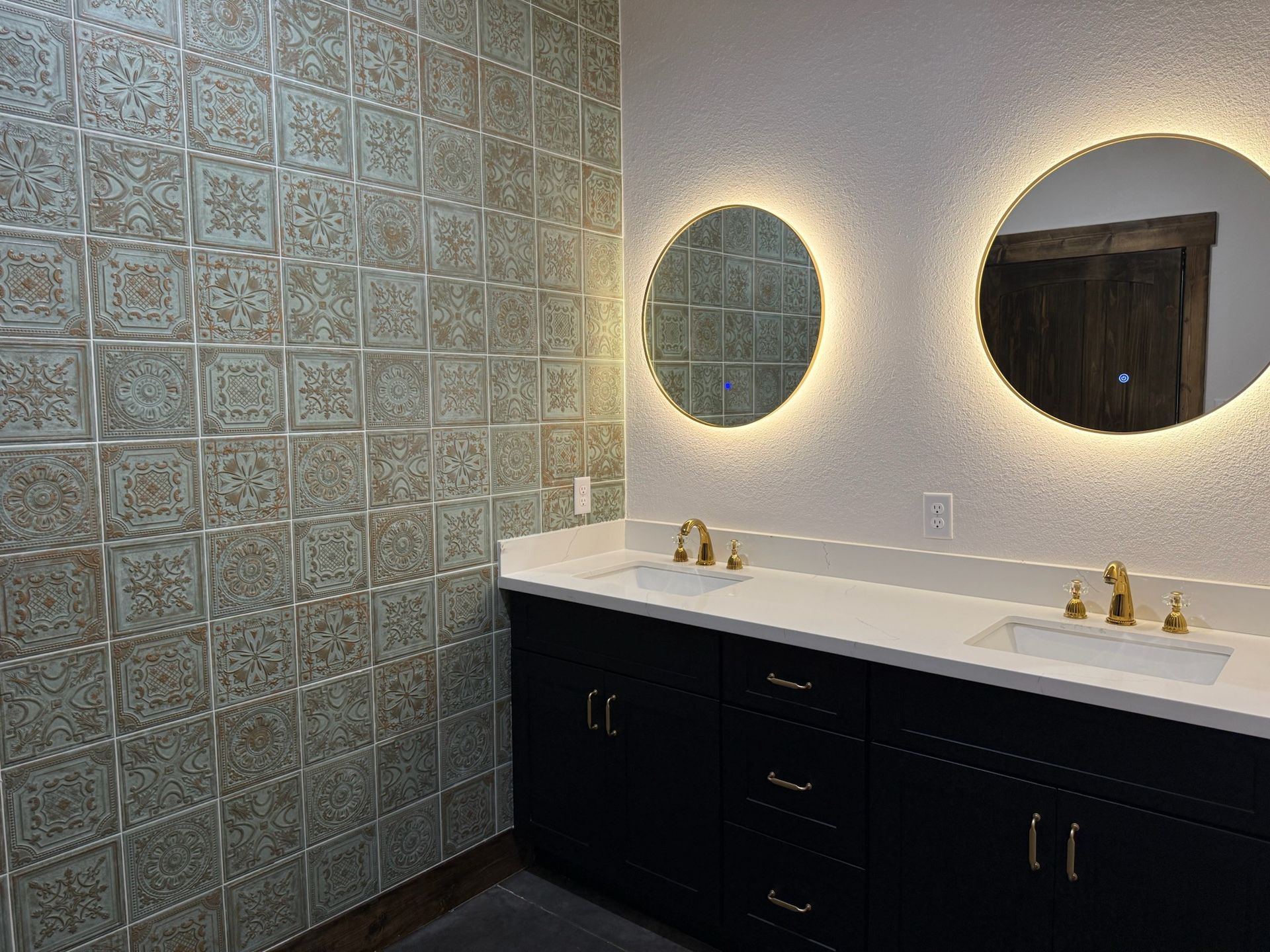 Modern bathroom vanity with double sinks, oval backlit mirror, and textured glass tile wall
