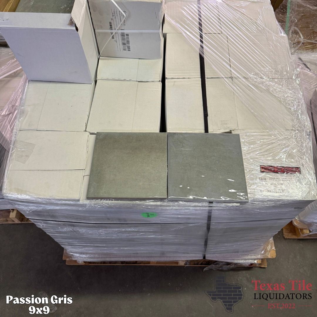 Stacked tile samples on a pallet, wrapped in plastic, with white and gray tiles visible.