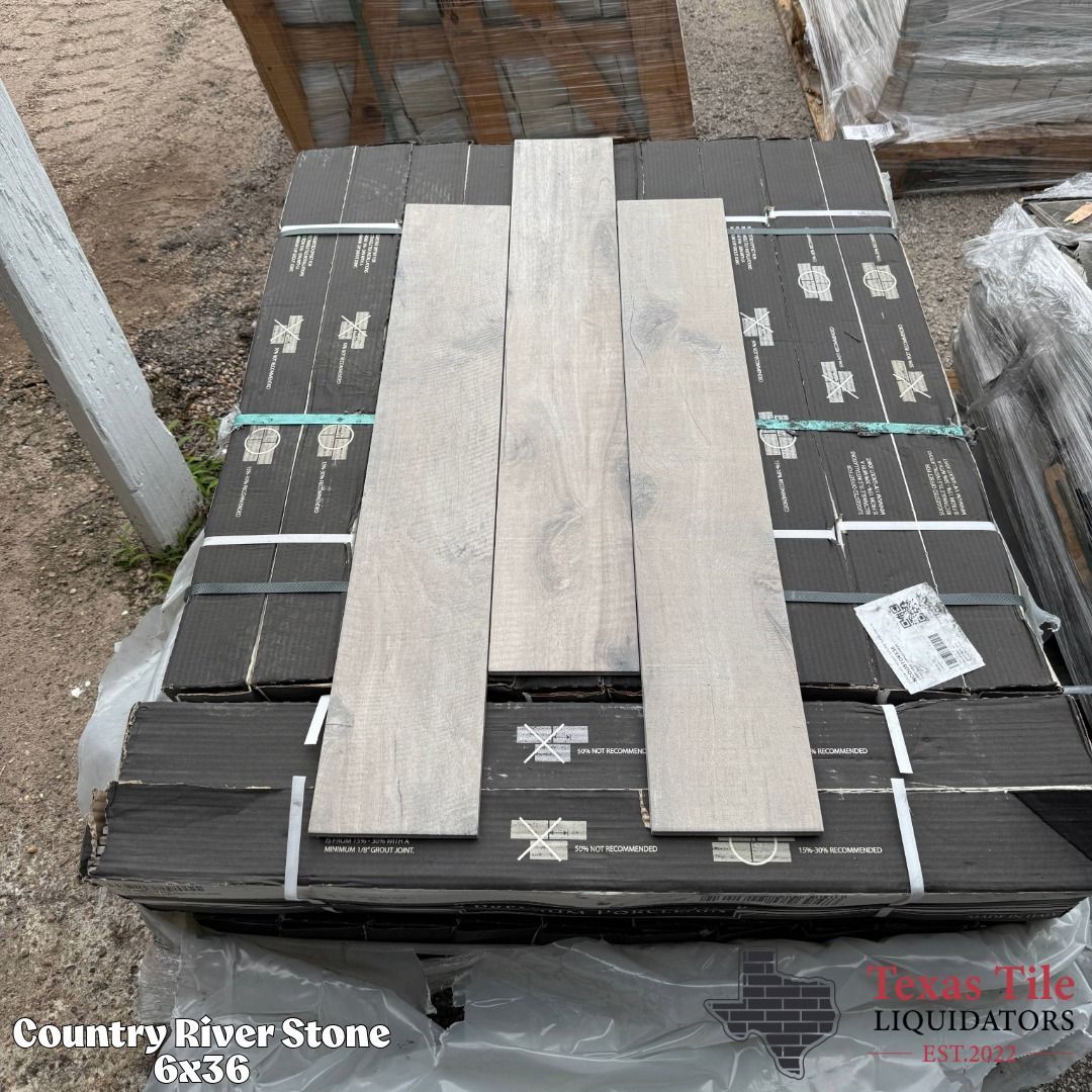 Stacked dark stone slabs with two light wood planks on top in an outdoor yard.