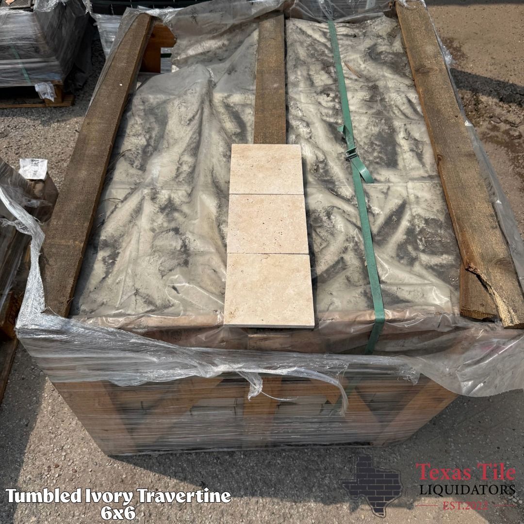 Shrink-wrapped stack of beige travertine tiles on a pallet with brown straps and green banding