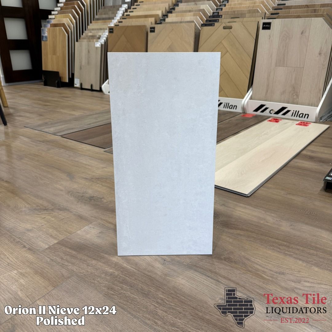White rectangular tile sample standing upright on a wood floor in a tile showroom.