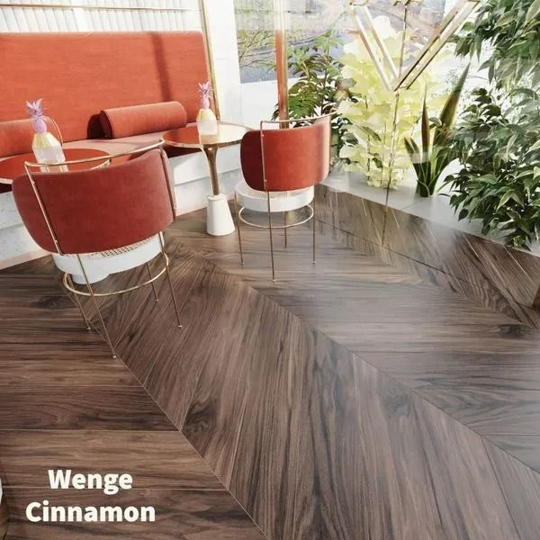 A cozy seating area with orange chairs and a booth featuring dark chevron-patterned wood flooring labeled Wenge Cinnamon.