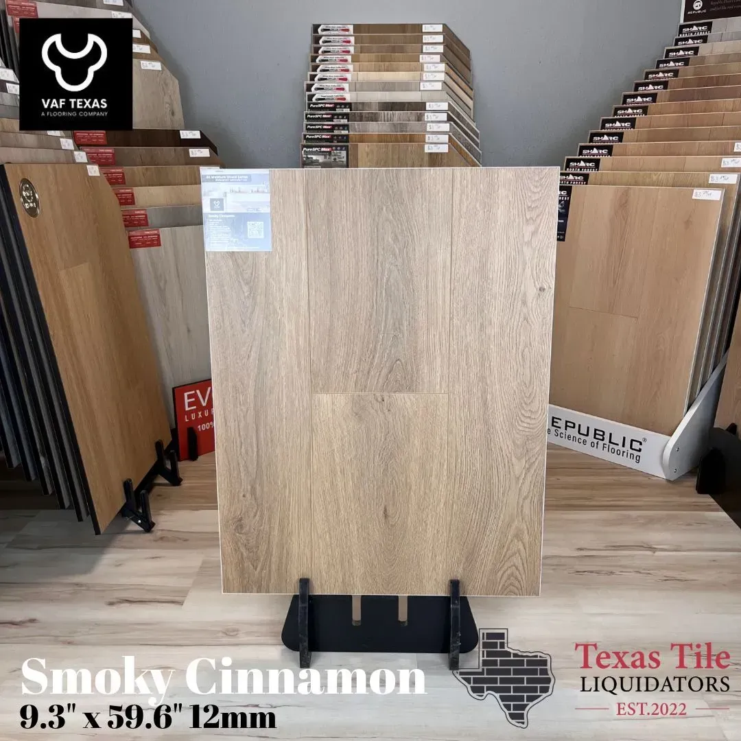 Light wood-look laminate sample displayed in a flooring showroom with stacked sample boards behind it.