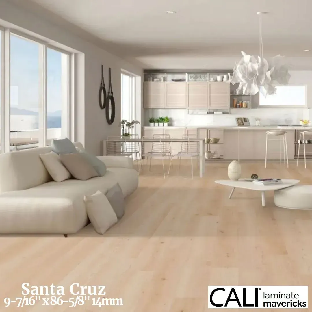 A modern, light-toned living room and kitchen featuring wide-plank, natural wood laminate flooring by CALI.
