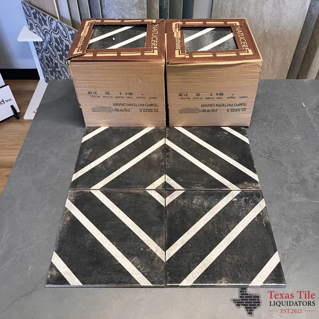 Four tiles arranged to form a geometric diamond pattern in front of two boxes of identical black and white patterned tiles.