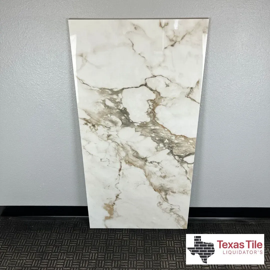 A single, rectangular white marble-look tile with prominent grey and brown veining displayed against a grey wall.