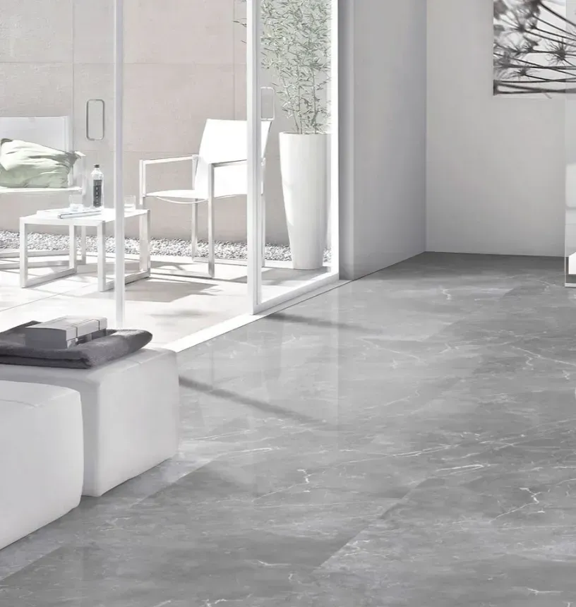 A bright room with polished gray marble-style flooring, transitioning to an outdoor patio with white furniture and plants.