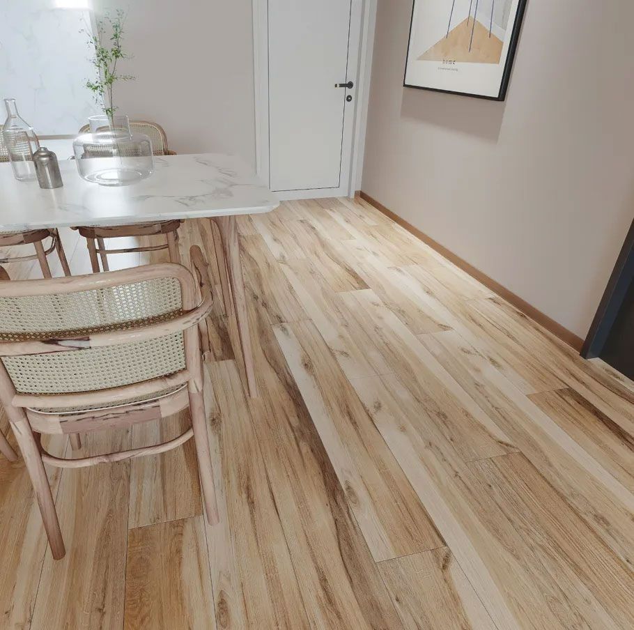 A modern dining area with a white marble-topped table, wooden chairs with woven backs, and light wood plank flooring.