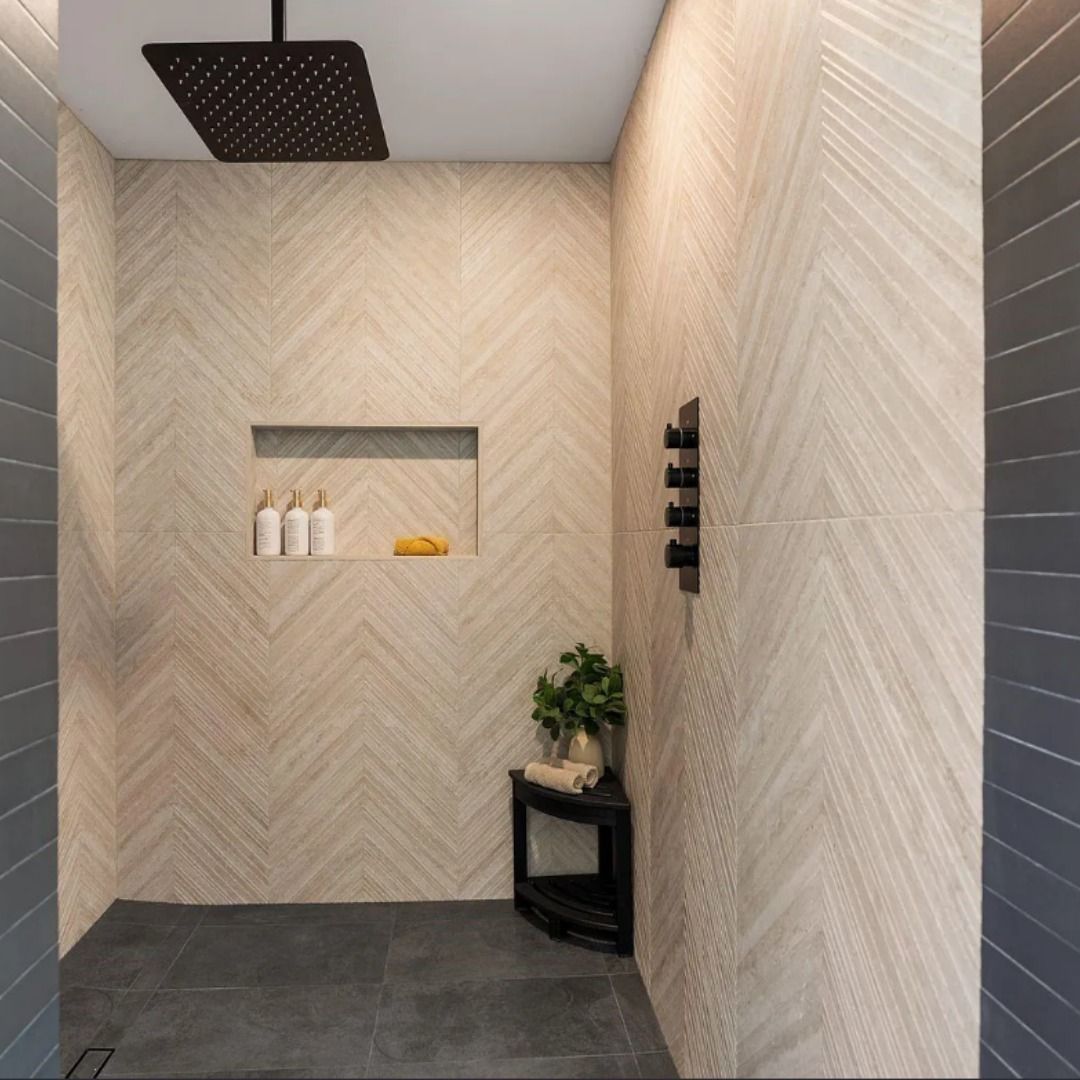Modern shower with light beige herringbone-patterned tile walls, dark gray floor tiles, a square rain head, and a niche.