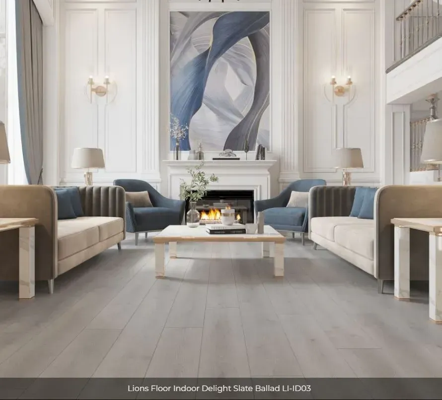 A bright, elegant living room with grey wood flooring, two beige sofas, blue armchairs, and a fireplace with artwork.